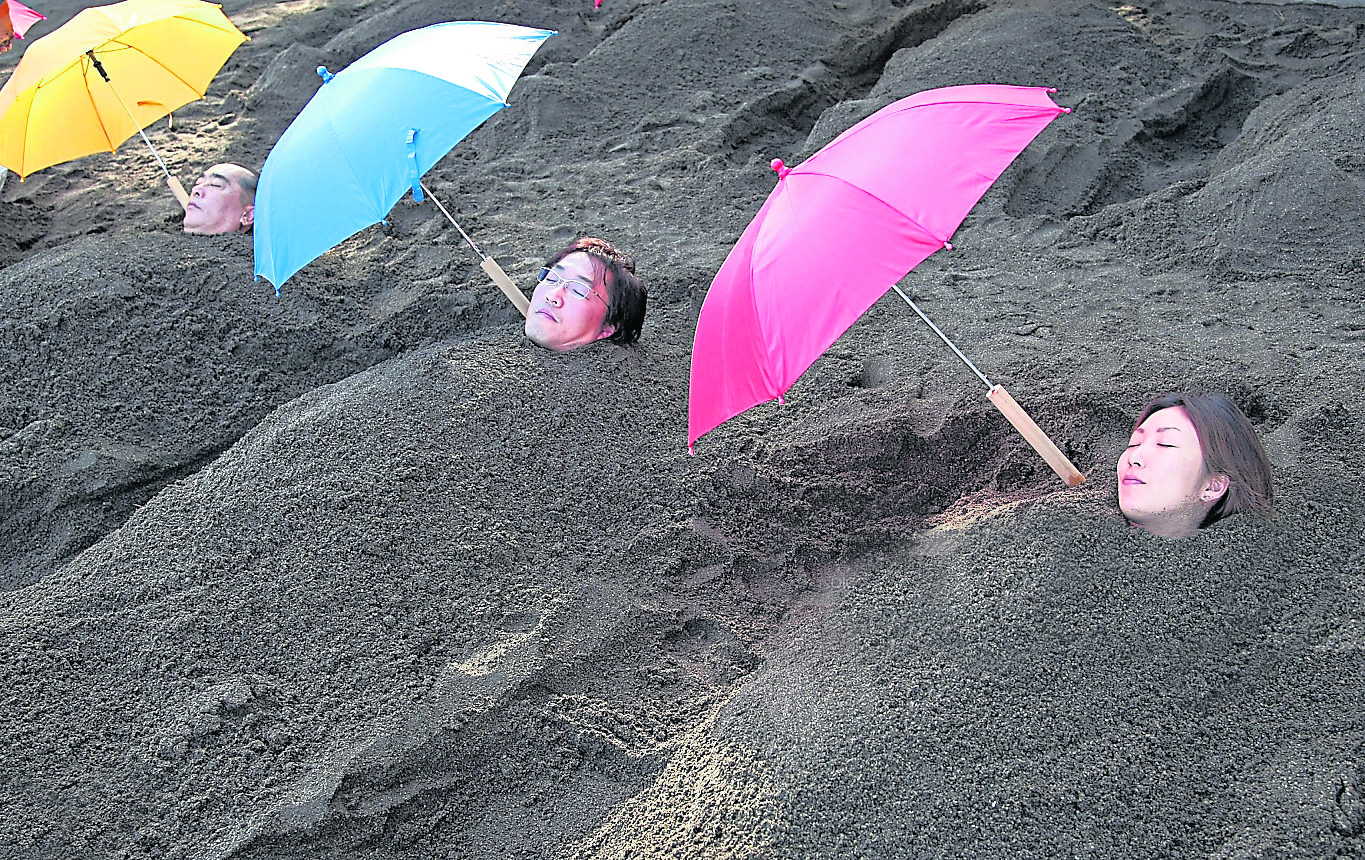 BEPPU, JAPAN - DECEMBER 03: People are buried to their neck in sand bath at Beppu Seafront Sand Spa on December 3, 2007 in Beppu, Oita, Japan. Customers are buried in natrually heated hot sand, the heated sand encourages perspiration. (Photo by Koichi Kamoshida/Getty Images)