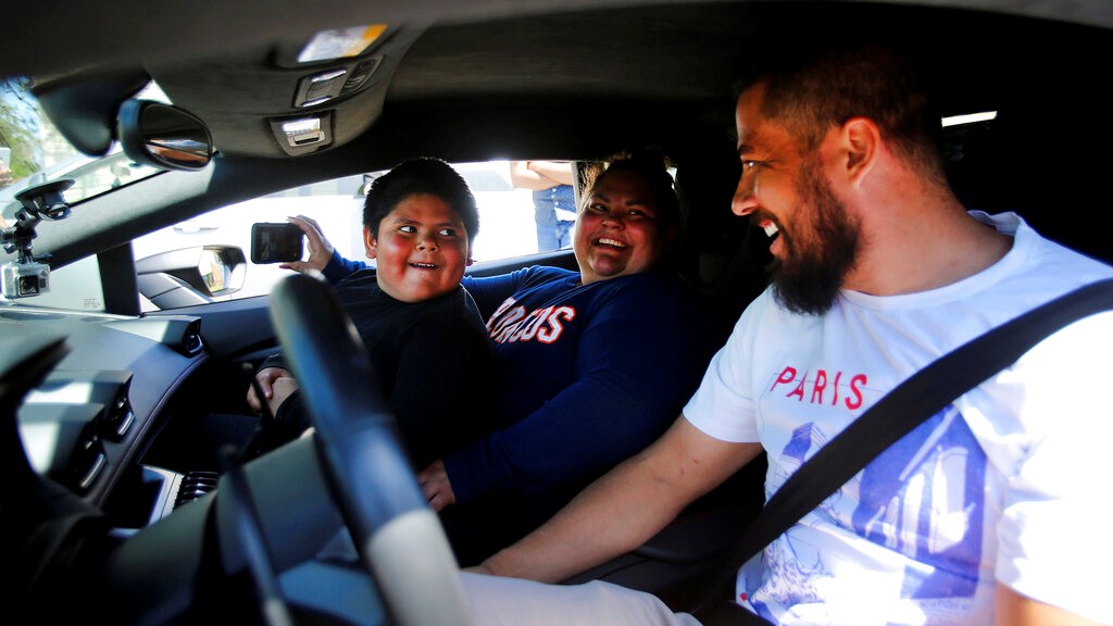 Adrian Zamarripa reacts after Adrian and his mother, Beatriz Flores, went for a ride in Jeremy Neves' Lamborghini Huracan in Ogden, Utah, Tuesday, May 5, 2020. Adrian, who tried to drive his parents' car to California Monday and was stopped by the Utah Highway Patrol, got the ride Tuesday from Neves who heard about the news and drove his car from another county. (Scott G Winterton/The Deseret News via AP)