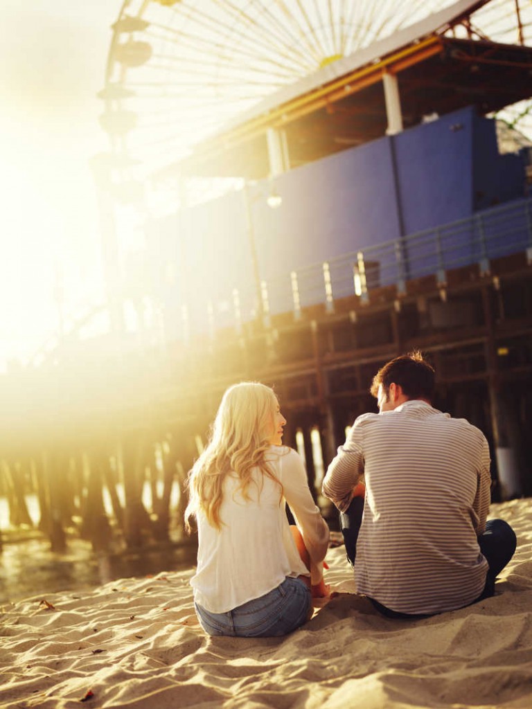 romantic couple sitting on beach with creative lens flare