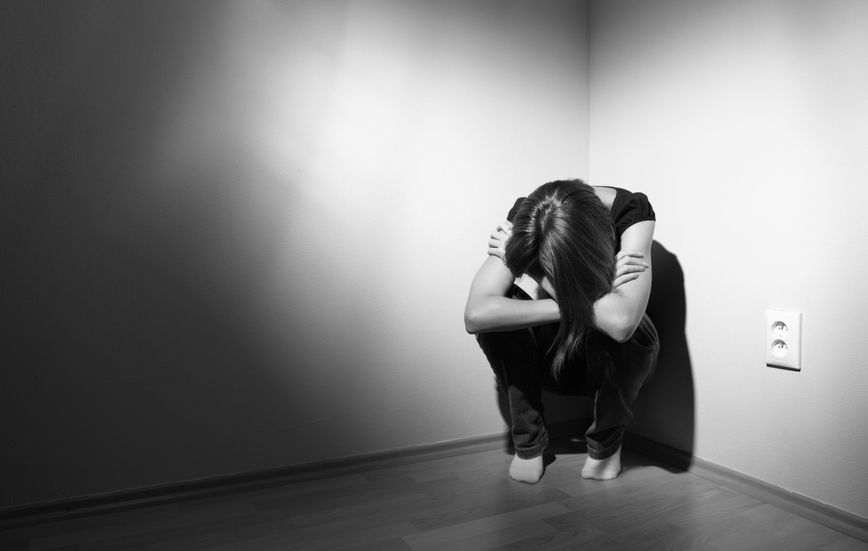 9793185 - young woman suffering from a severe depression (very harsh lighting is used on this shot to underline/convey the gloomy mood of the scene)