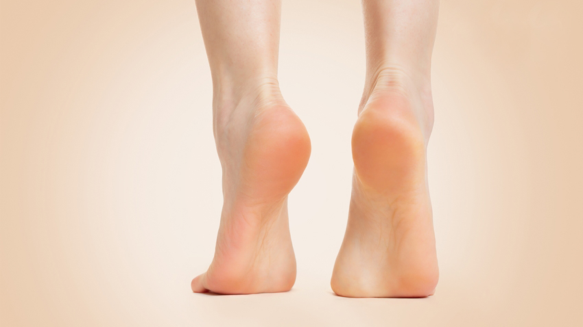 Beautiful female feet, with smooth and soft heels, close-up on a beige background. Copy space. Back view. Concept of cosmetology, dermatology and health