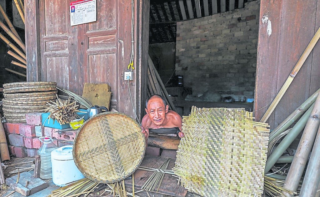李佰洲在展示自己做的竹编，他编织的不只是竹器，而是生活、是梦想。