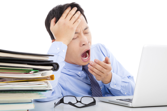 Exhausted young businessman yawning and holding his head