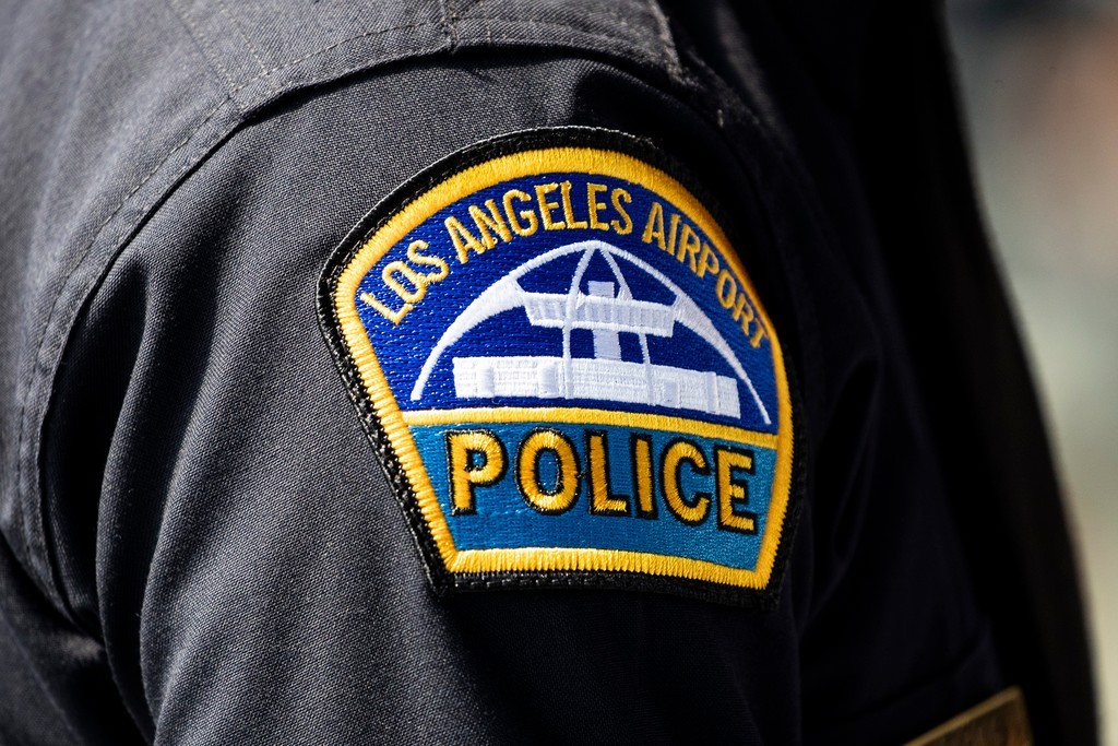 epa09458497 The badge of a Los Angeles Airport Police officer is photographed as the recruiter converses with job seekers during the hiring fair for the aviation sector organized by LAX (Los Angeles Airport) and SoFi Stadium at the SoFi Stadium in Los Angeles, California, USA, 09 September 2021. According to organizers of the fair, more than 5,000 positions in airlines, concessions, retail, administration and more will by offered for applicants.  EPA-EFE/ETIENNE LAURENT