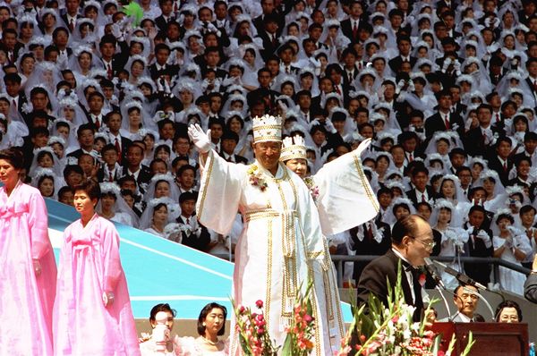 FILE - In this Aug. 25, 1992 file photo, Unification Church founder Rev. Sun Myung Moon and his wife wave their hands to some 40,000 believers and supporters during a wedding ceremony at Seoul's Olympic Stadium in Seoul, South Korea. The aging Rev. Sun Myung Moon, one of the world's most controversial Christian figures, is moving to turn over control of his Unification Church to his three Harvard-educated sons. (AP Photo/Ahn Young-Joon, File)