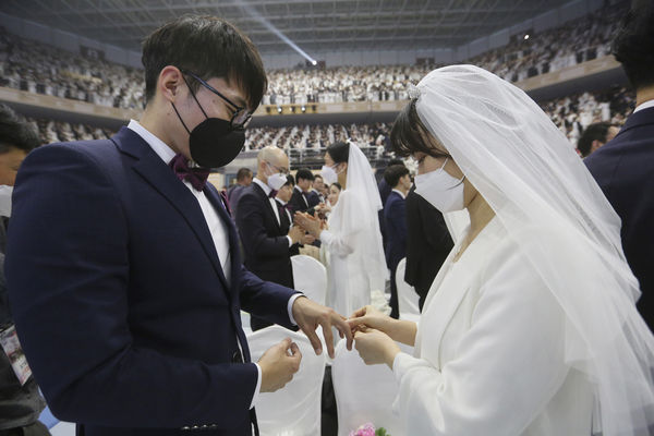 A couple wearing face masks exchanges their rings in a mass wedding ceremony at the Cheong Shim Peace World Center in Gapyeong, South Korea, Friday, Feb. 7, 2020. South Korean and foreign couples exchanged or reaffirmed marriage vows in the Unification Church's mass wedding arranged by Hak Ja Han Moon, wife of the late Rev. Sun Myung Moon, the controversial founder of the church. (AP Photo/Ahn Young-joon)