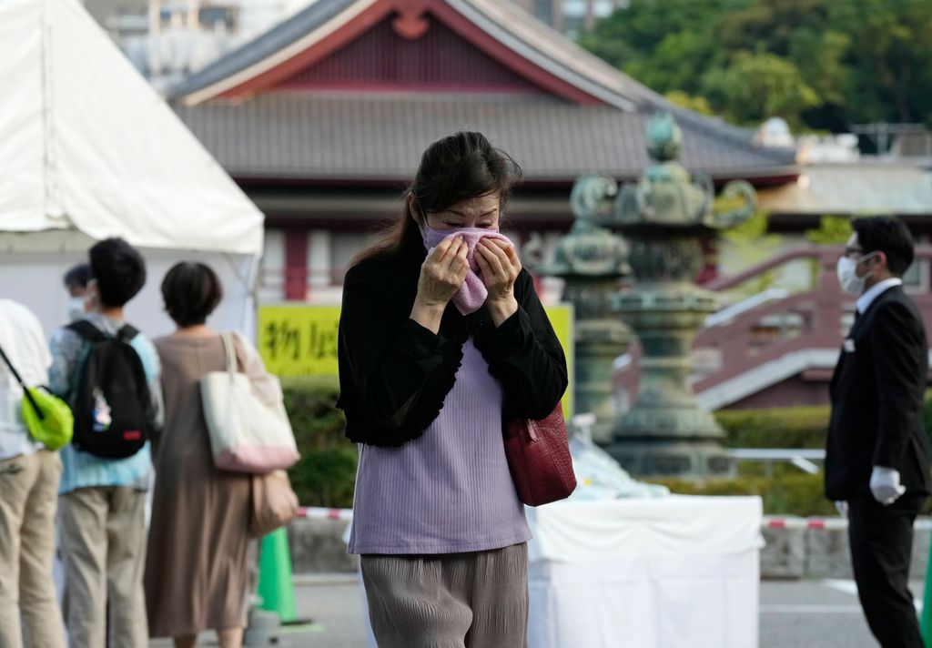 一名女性11日在东京增上寺悼念安倍晋三，离开时用手帕捂脸。