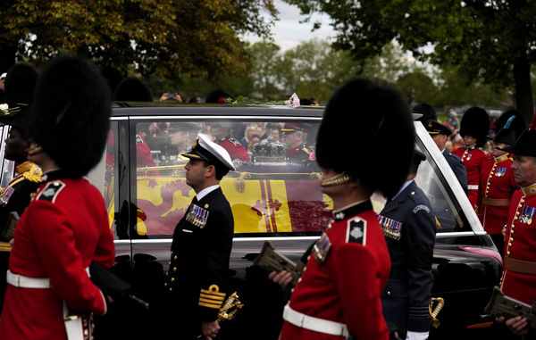 Grenadier Guards march alongside the hearse carrying the coffin of Queen Elizabeth II as it arrives on the Long Walk outside Windsor Castle in Windsor, England, Monday, Sept. 19, 2022. The Queen, who died aged 96 on Sept. 8, will be buried at Windsor alongside her late husband, Prince Philip, who died last year. (AP Photo/Alastair Grant, Pool)