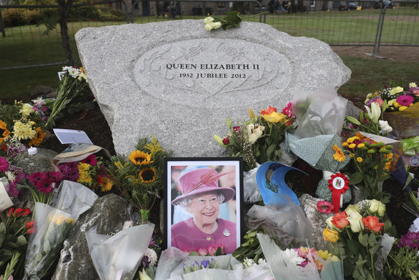 Floral tributes are placed in Ballater, Scotland ahead of the hearse carrying the coffin of Queen Elizabeth II before it passes through to make its journey to Edinburgh from Balmoral in Scotland, Sunday, Sept. 11, 2022. The Queen's coffin will be transported Sunday on a journey from Balmoral to the Palace of Holyroodhouse in Edinburgh, where it will lie at rest before being moved to London later in the week. (AP Photo/Scott Heppell)