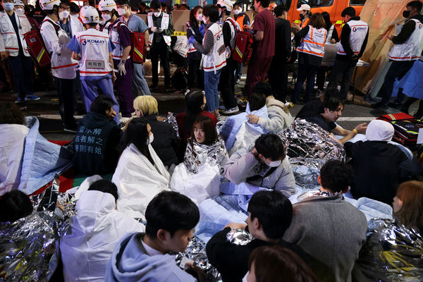 People sit on the street after being rescued, at the scene where dozens of people were injured in a stampede during a Halloween festival in Seoul, South Korea, October 29, 2022. REUTERS/Kim Hong-ji