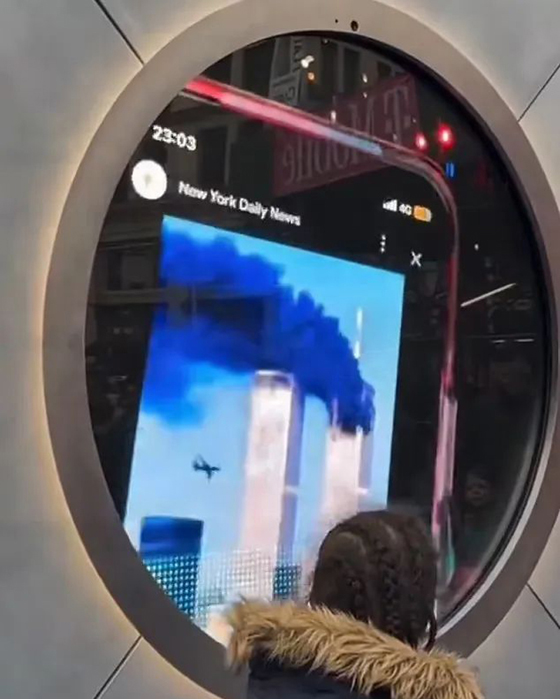 爱尔兰人在“传送门”前向纽约民众展示911恐怖袭击双子塔着火的视频。