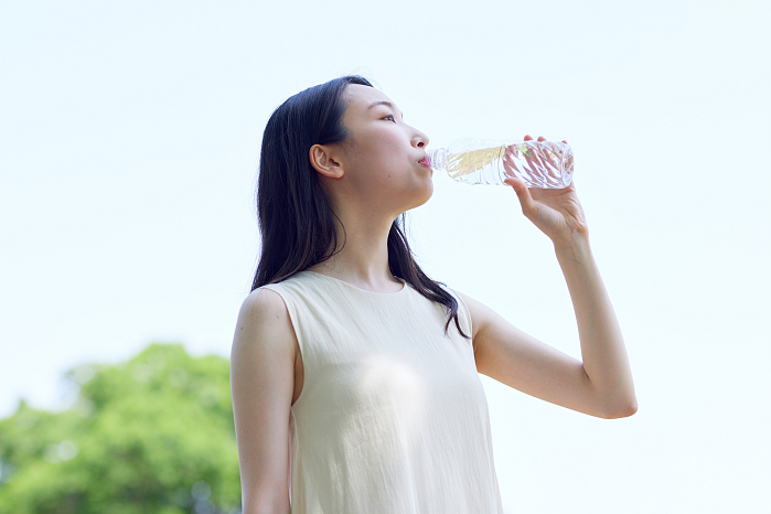 Young Japanese woman drinking water outside