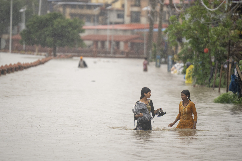 Women walk with their belongings on the flooded banks of the Bagmati river following heavy monsoon rains in Kathmandu, Nepal, Saturday, July 6, 2024. (AP Photo/Niranjan Shrestha)