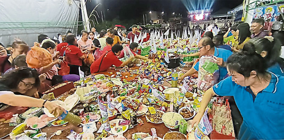 华印裔村民及小孩蜂涌围绕福品长桌，抢夺包装零食和三牲祭品，大袋小袋场面壮观。