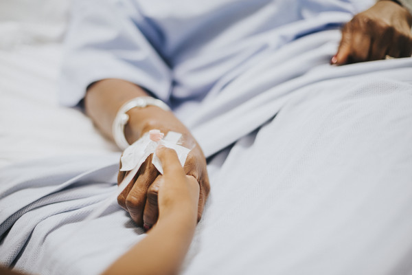 Daughter holding her mothers hand in the hospital